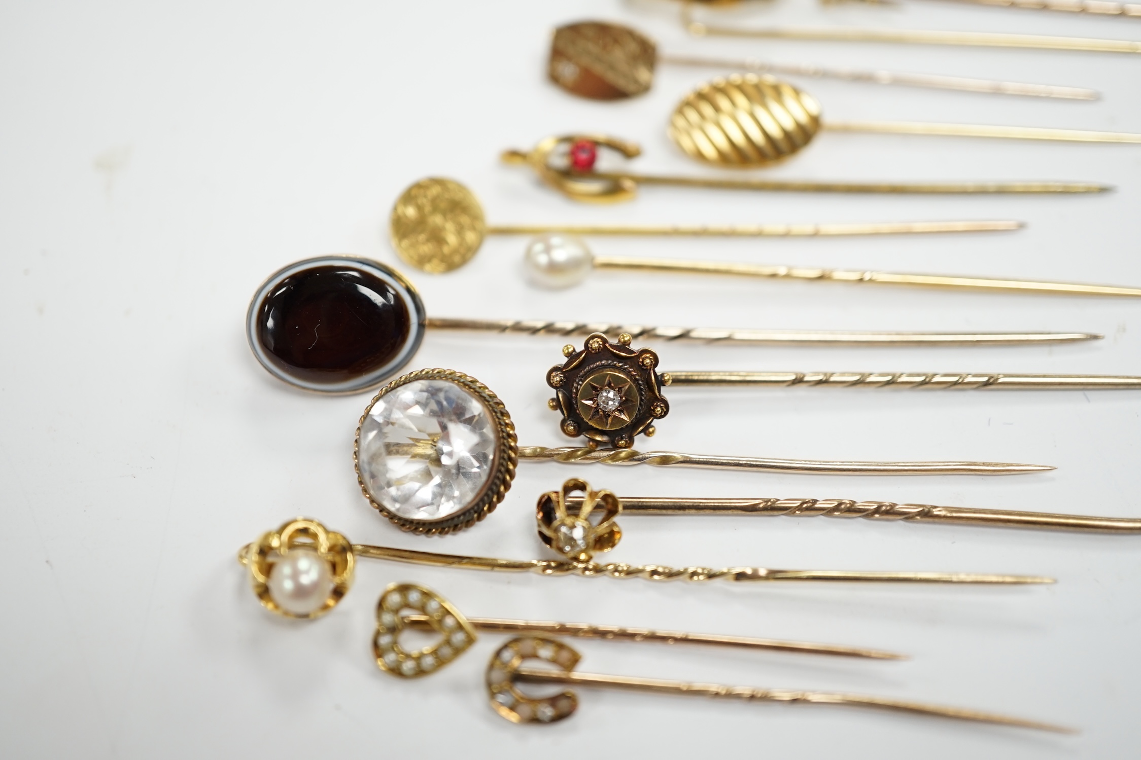 Fifteen assorted mainly early 20th century yellow metal and gem set stick pins, including diamond, seed pearl and banded agate, gross weight 23.1 grams.